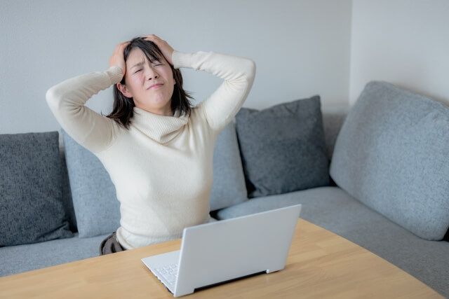 パソコンの前で頭を抱える女性