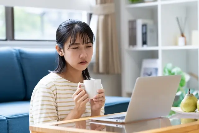 パソコンの画面を疲れている表情で見ている女性