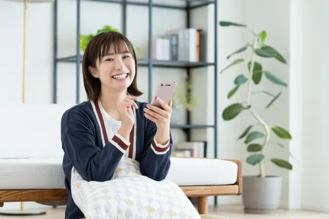 スマホを持って笑顔の女性